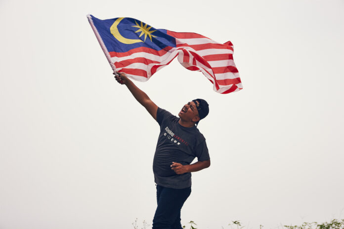 Man in black t shirt holding flag of malaysia