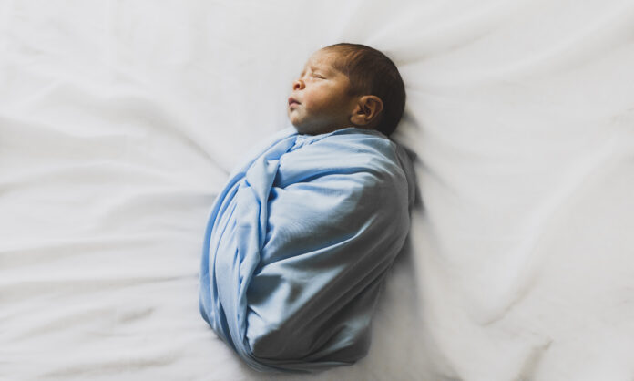 Photo of new born baby covered with blue blanket