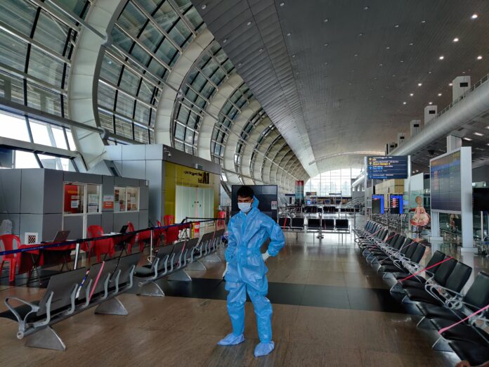 Man wearing PPE at an empty airport during COVID times. COVID and Travel.